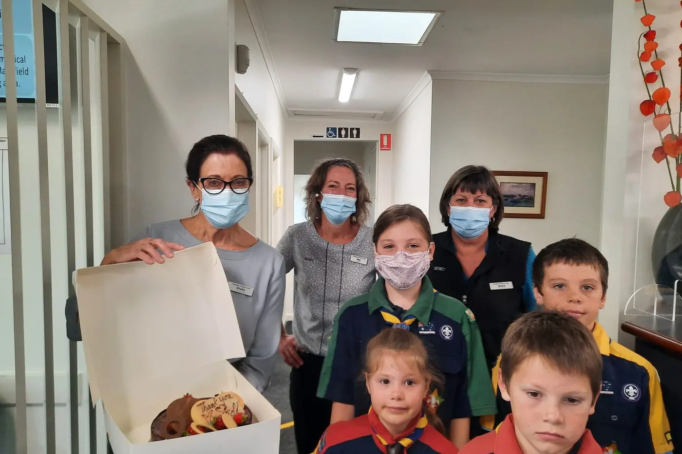 MASKED SMILES: Ella, Josiah, Pippa and Micah from the Scouts delivering a cake to the staff of the Medical Clinic.